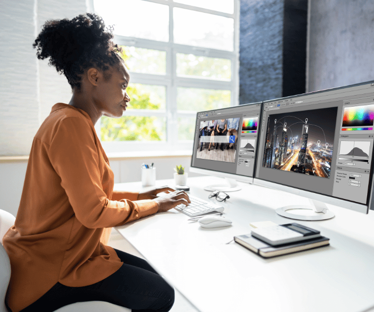 Black woman sits at a desktop computer designing the visual elements of a website