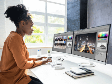 Black woman sits at a desktop computer designing the visual elements of a website