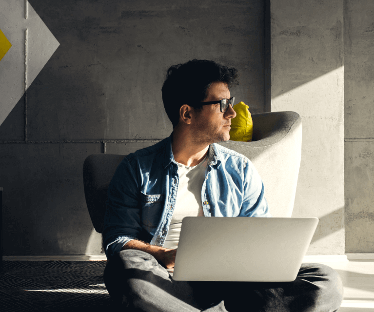 Male freelance with a laptop gazing out of the window