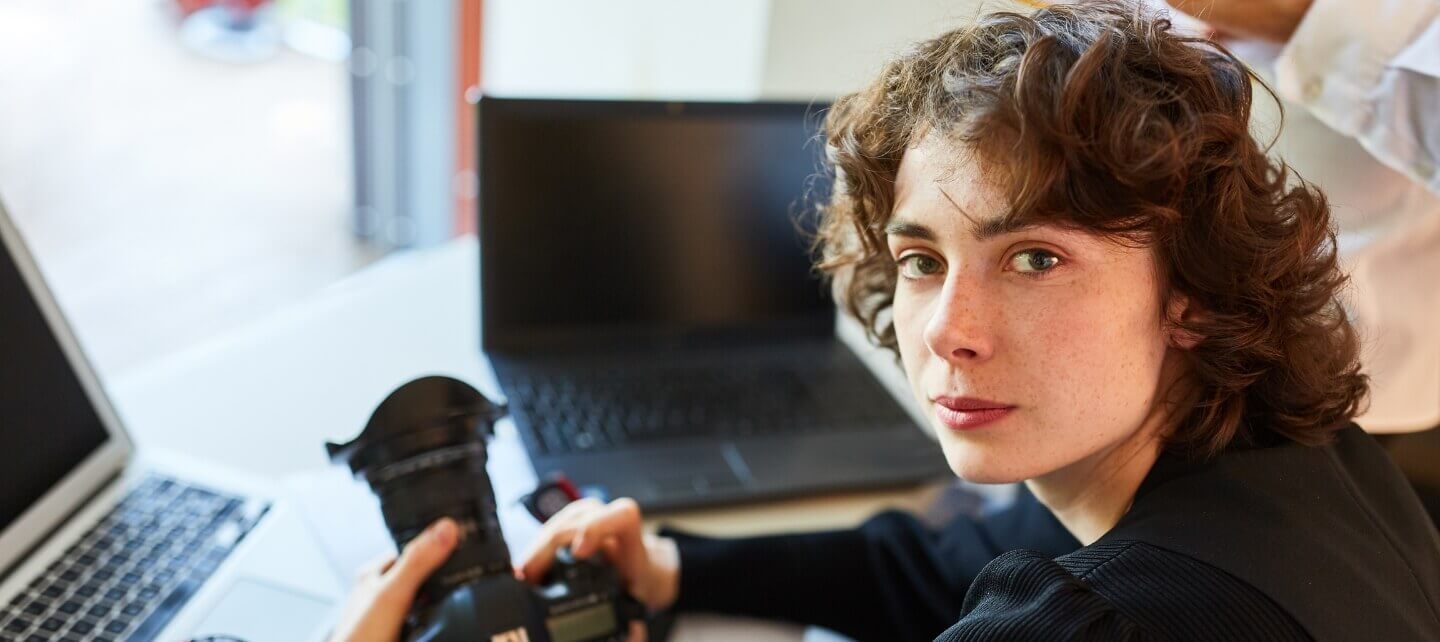 Self-employed photographer working on laptop, representing freelancers and contractors seeking insurance protection in the UK.