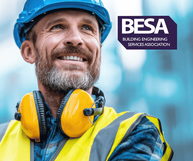 Construction worker on a construction site wearing a hardhat, ear defenders and a high-visibility vest