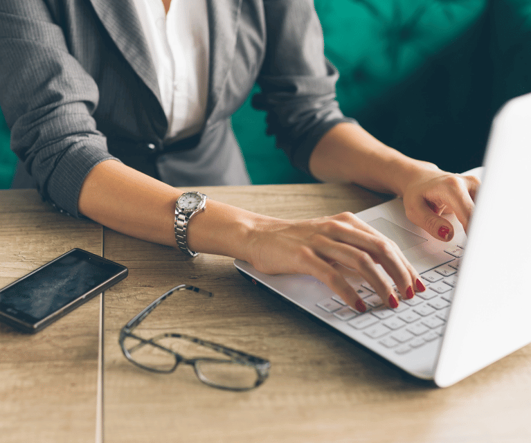 Image of person in business clothes using a laptop at a table, representing business equipment insurance